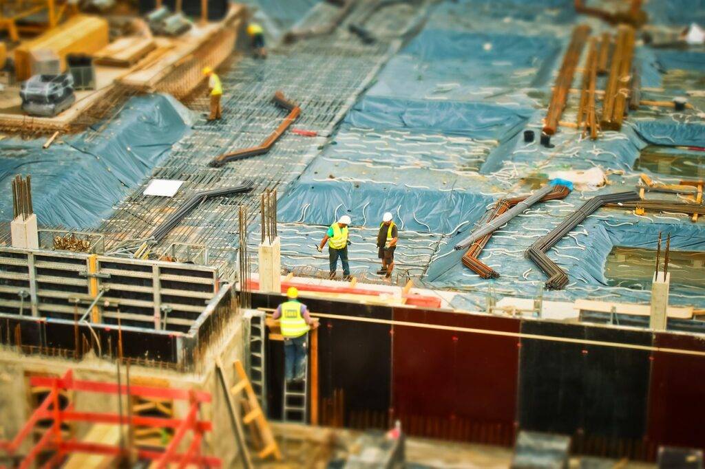 Construction workers on a blue tarp-covered area at a construction site