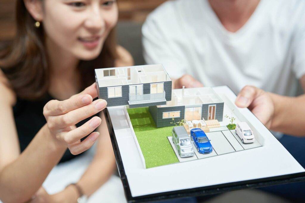 Three-dimensional architectural model of a house with landscaping and a blue car